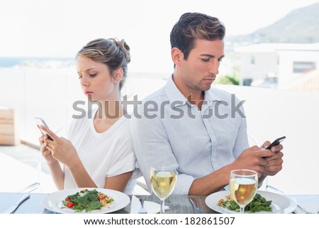 Concentrated young couple text messaging at food table