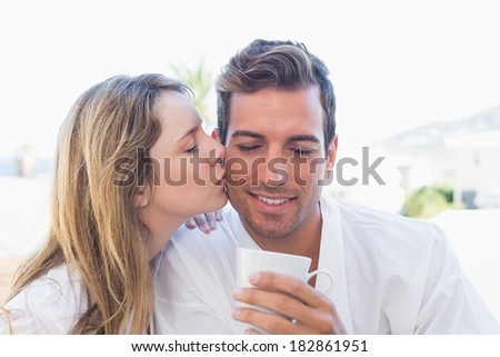 Close-up of a young woman kissing man while having coffee in the house