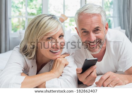 Close-up portrait of a cheerful mature couple reading text message at home