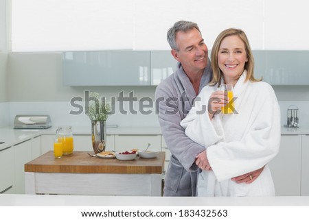 Smiling man embracing woman from behind in the kitchen at home