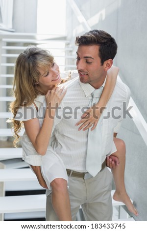 Smiling young man carrying woman against stairs at home