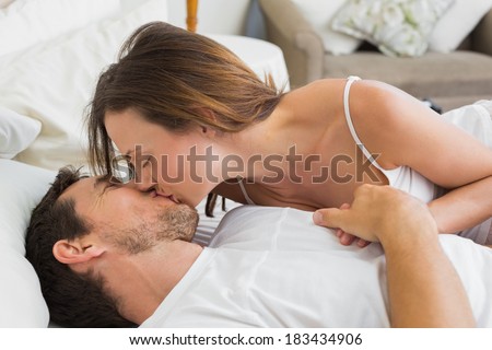 Relaxed young couple kissing in bed at home