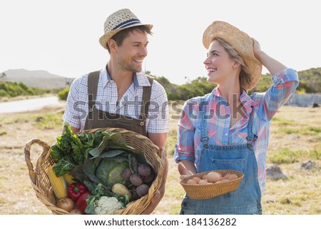 Portrait of a smiling young couple with vegetables standing in the field