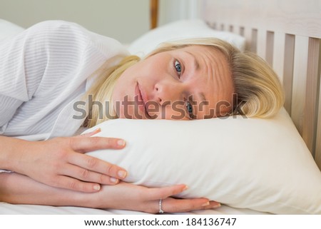 Portrait of sleepy woman lying in bed at home