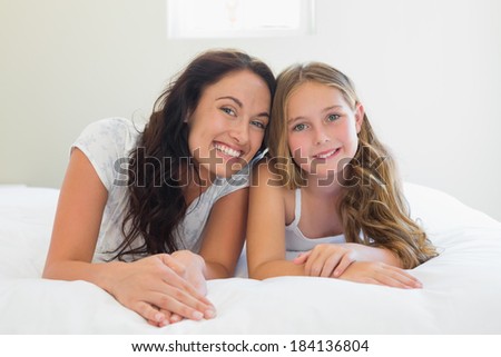 Portrait of mother with cute daughter lying in bed at home