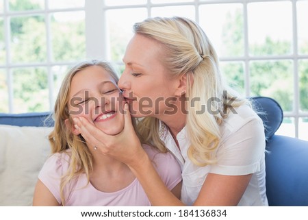 Blond woman kissing daughter on cheek at home
