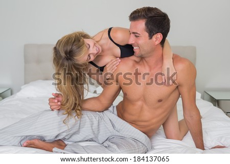 Cheerful romantic young couple in underwear in bed at home