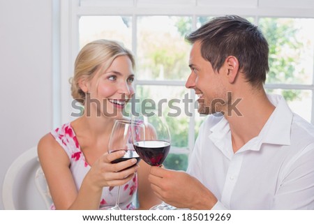 Happy loving young couple with wine glasses looking at each other at home