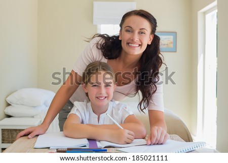 Portrait of happy mother and mother at studying table in house