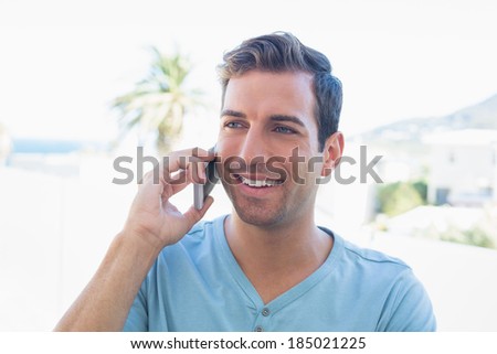 Close-up portrait of a smiling young man using mobile phone