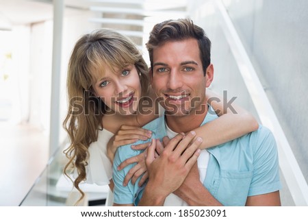 Portrait of a loving young woman embracing man from behind at home