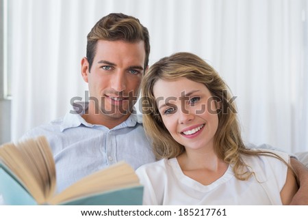 Close-up of a relaxed young couple reading book on couch at home