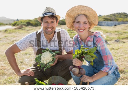 Portrait of a smiling young couple with fresh vegetables in the field