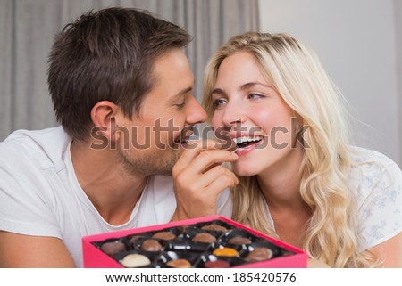 Relaxed happy young couple eating candies at home
