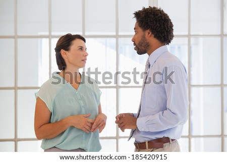 Two young business people having a conversation in the office
