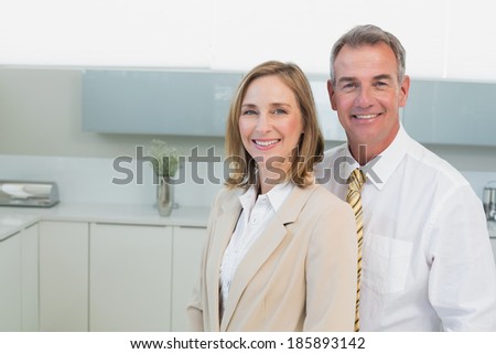 Portrait of a happy business couple standing in the kitchen at home
