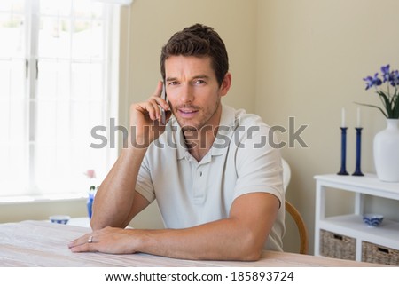 Portrait of a relaxed smiling young man using mobile phone at home