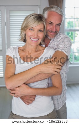 Portrait of a mature man embracing woman from behind at home