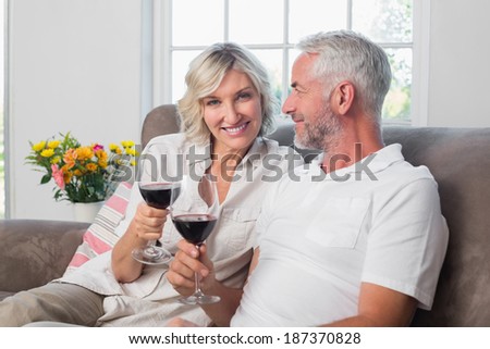 Happy loving mature couple with wine glasses in the living room at home