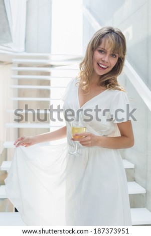 Portrait of a beautiful young woman with wine glass on stairs at home