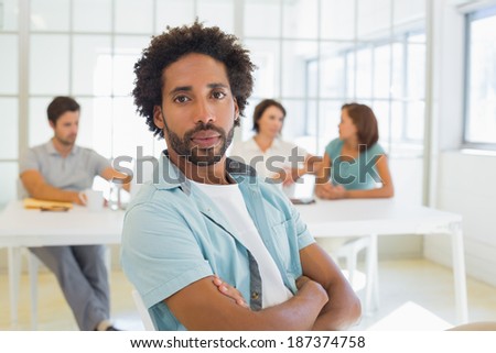 Portrait of a serious businessman with colleagues in meeting in background at the office