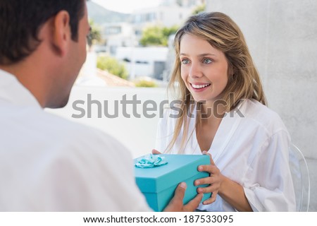 Young man giving happy woman a gift box at home