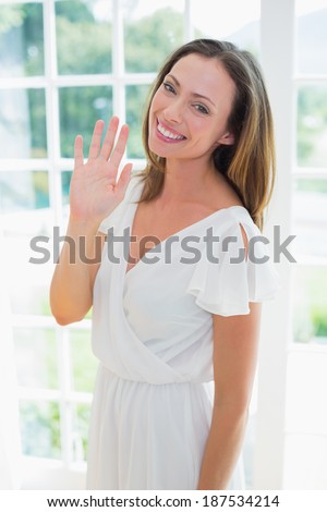 Portrait of a smiling relaxed young woman waving hand at home