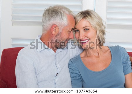 Relaxed smiling mature couple sitting on couch at home