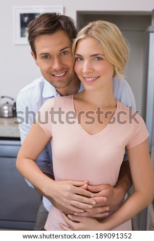 Portrait of a smiling young man embracing woman from behind at home
