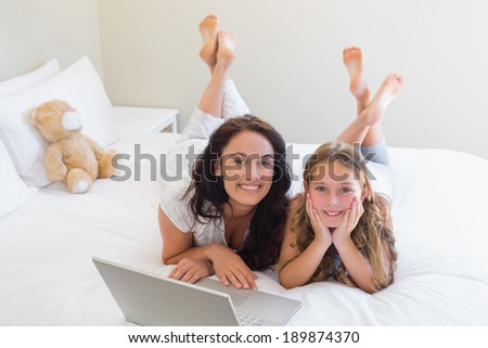 Full length portrait of mother and daughter lying in bed at home