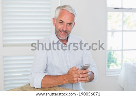 Portrait of a relaxed mature man text messaging at home