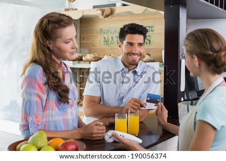 Side view of a couple paying bill at coffee shop using card bill