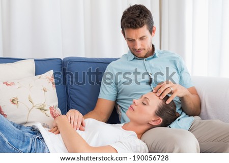 Relaxed young woman resting on mans lap on couch at home