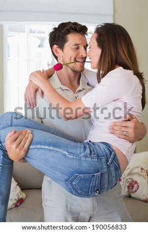 Smiling young man carrying woman at home