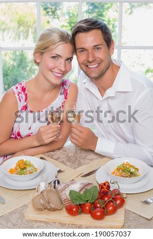 Portrait of a happy loving young couple with wine glasses at dining table at home