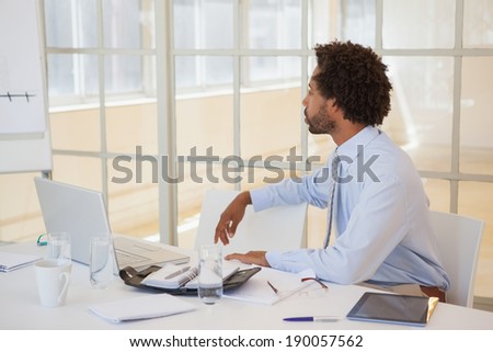 Side view of a serious businessman sitting at office desk