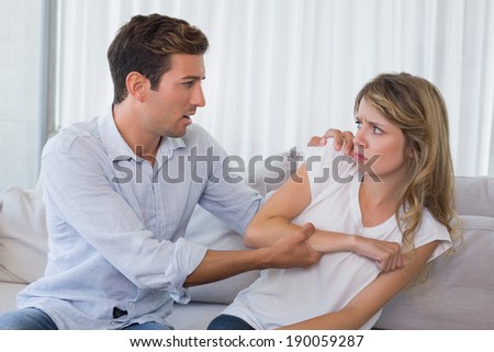 Young man consoling a sad woman in the living room at home