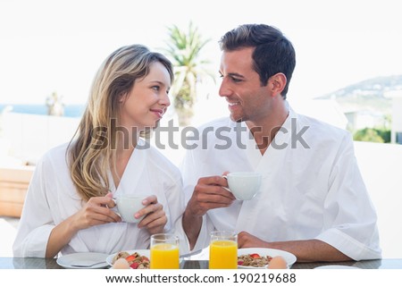 Smiling young couple looking at each other while having breakfast at home