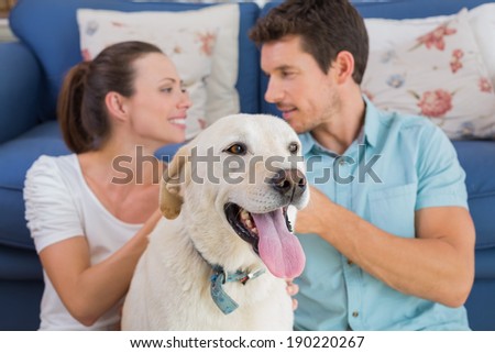 Loving relaxed young couple with pet dog sitting in living room at home