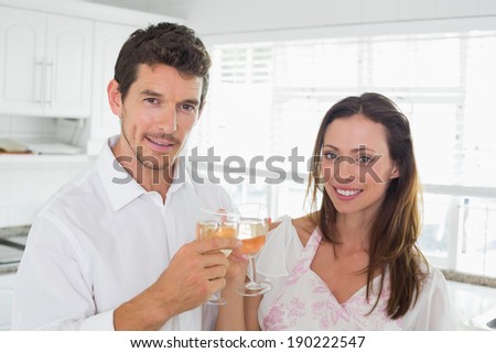 Portrait of a loving young couple toasting wine glasses in kitchen at home
