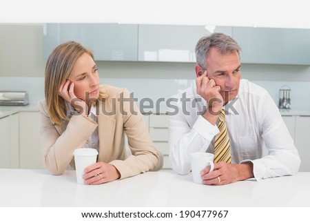 Unhappy business couple not talking after an argument in the kitchen at home