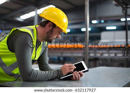 Factory worker using digital tablet at drinks production factory