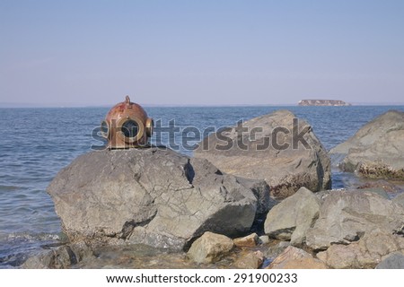 Vintage diving helmet on the rocky seashore.