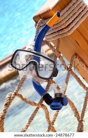 Blue Snorkeling equipment hanging on a rope, swimming pool on the background.