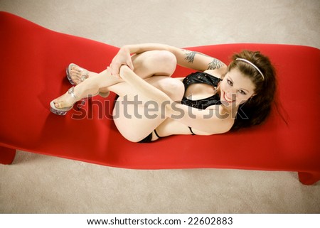 sexy pin-up girl lying on red couch from above