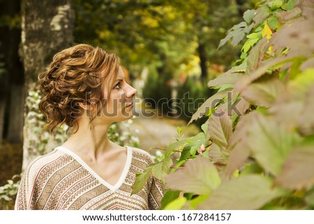 Autumn portrait of beautiful young woman looking to the left in the garden