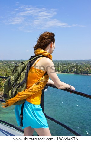 Young beautiful woman by lighthouse Dondra Head at Matara, looking at beautiful Indian ocean seascape of Sri Lanka coastline, Ceylon