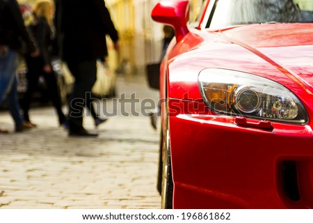 Fragment of red sport car with headlight in sunlight at sunset