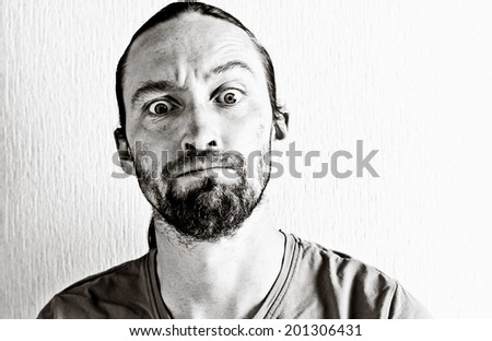Portrait of surprised young man in studio at white background. Image toned in black and white colors