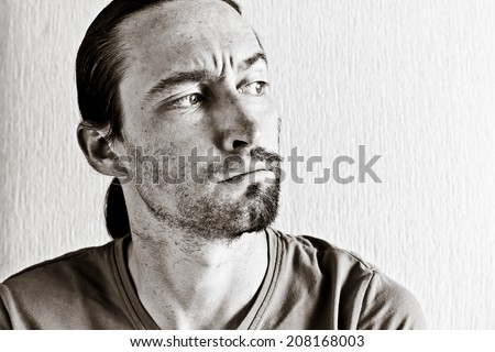 Studio Portrait of young man looking far away with half shaved face. Image toned in black and white colors